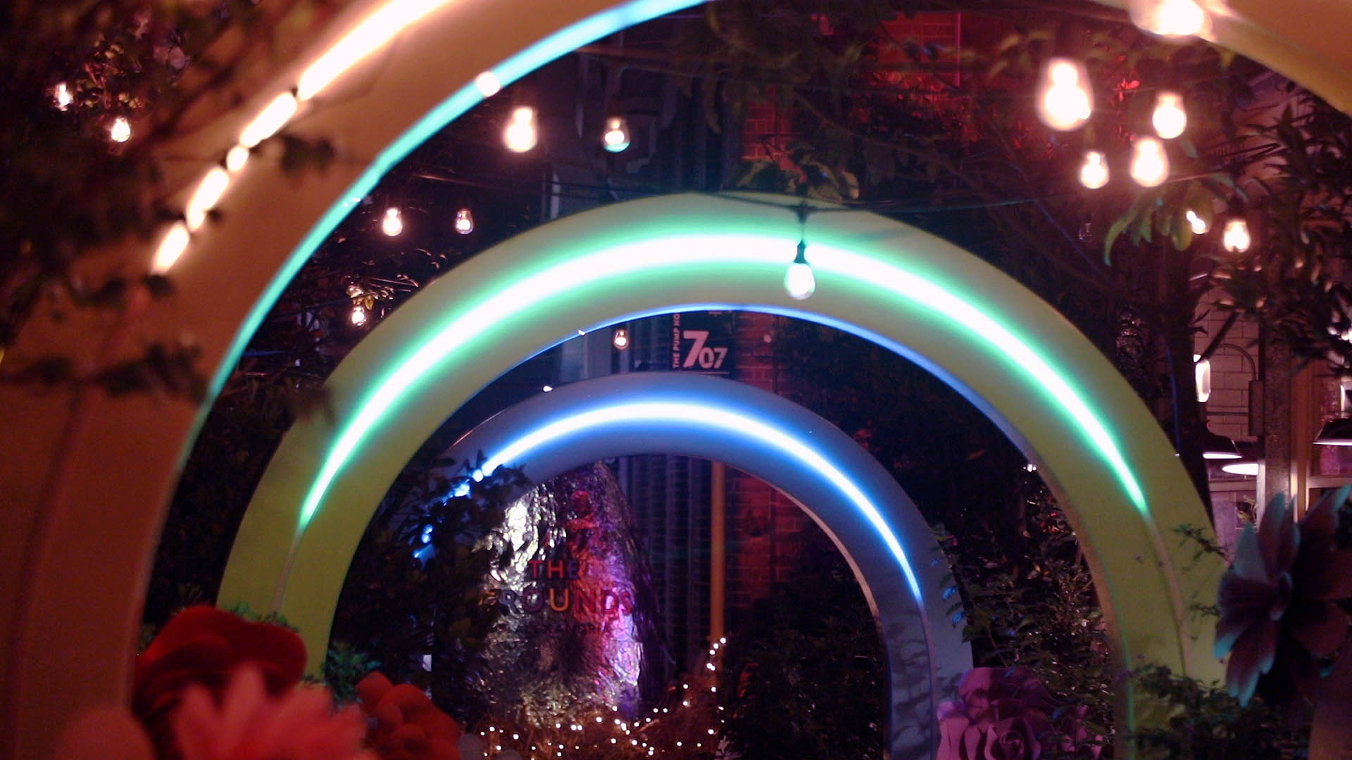 The Grounds of Alexandria arch walkway lit with colour-changing light at night